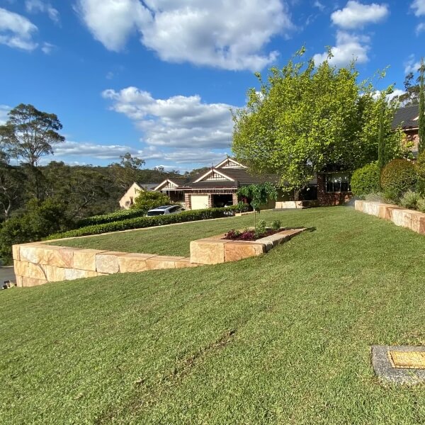 Retaining walls and landscaping in Western Sydney featuring sandstone block terraces and freshly laid lawn by West Sydney Landscapes.