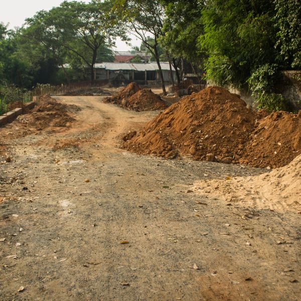 Roadbase driveway construction in Western Sydney with soil mounds and graded access road under preparation by West Sydney Landscapes.