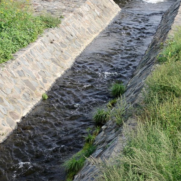 Swale drain and drainage construction in Western Sydney with stone-lined channel managing stormwater flow by West Sydney Landscapes.